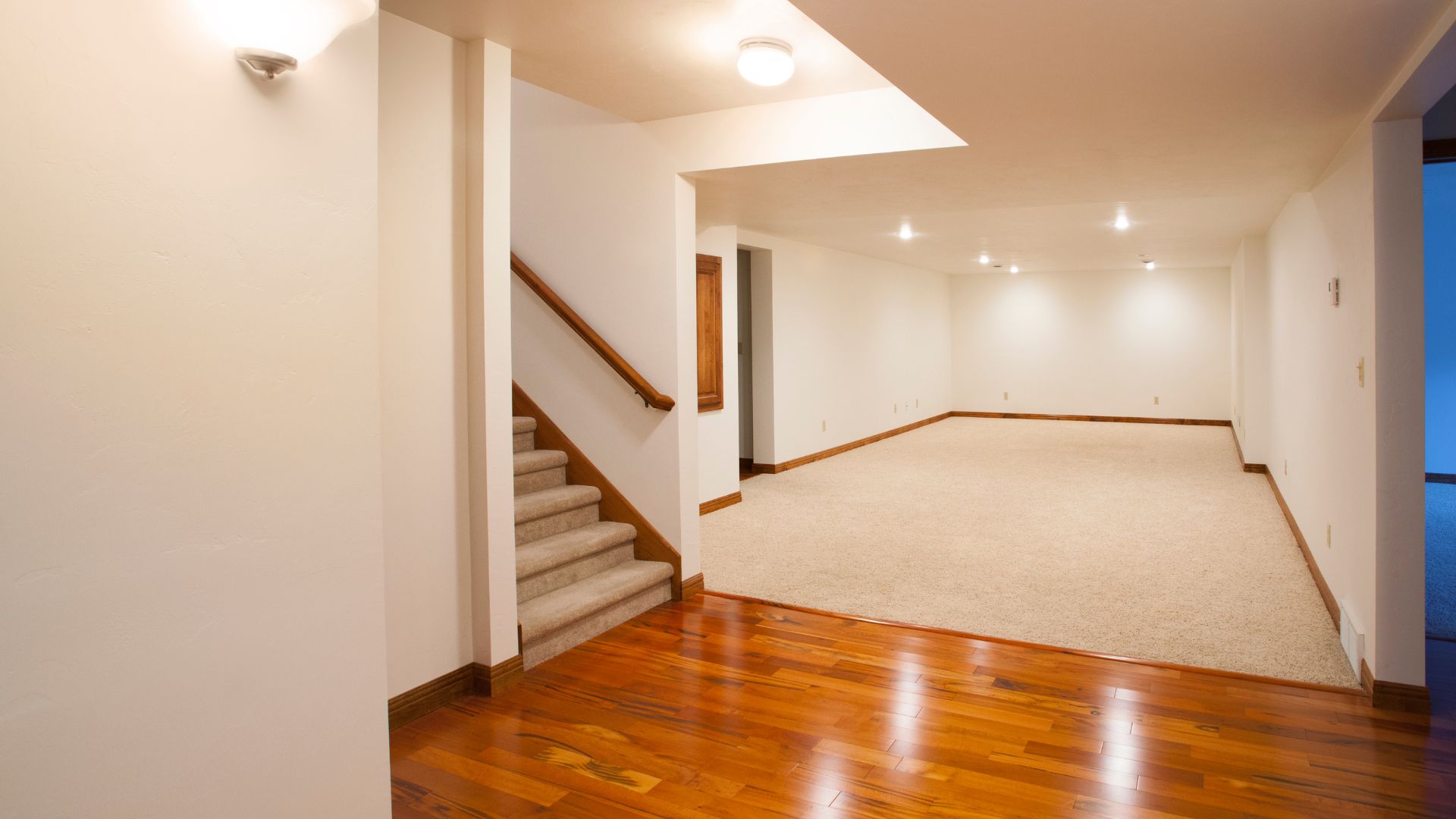 A large empty room with a staircase leading to a second floor